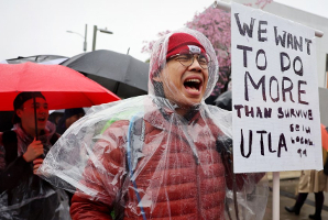 Los Angeles/USA - streikende Lehrerin im Regen mit Schild: "Wir wollen mehr tun als nur zu überleben"