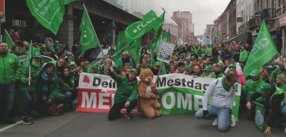 Belgien: Demonstration von Supermarktkolleg*innen von Delhaize mit grünen Bannern und Fahnen