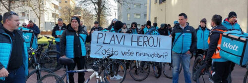 In Wolt-Uniform gekleidete Männer in Zagreb/ Koratien halten ein Plakat hoch im Streik mit "Blaue Helden - warum sind wir nicht gut genug?"
